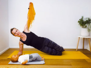 Mama mit Baby beim Sport auf einer Matte am Boden
