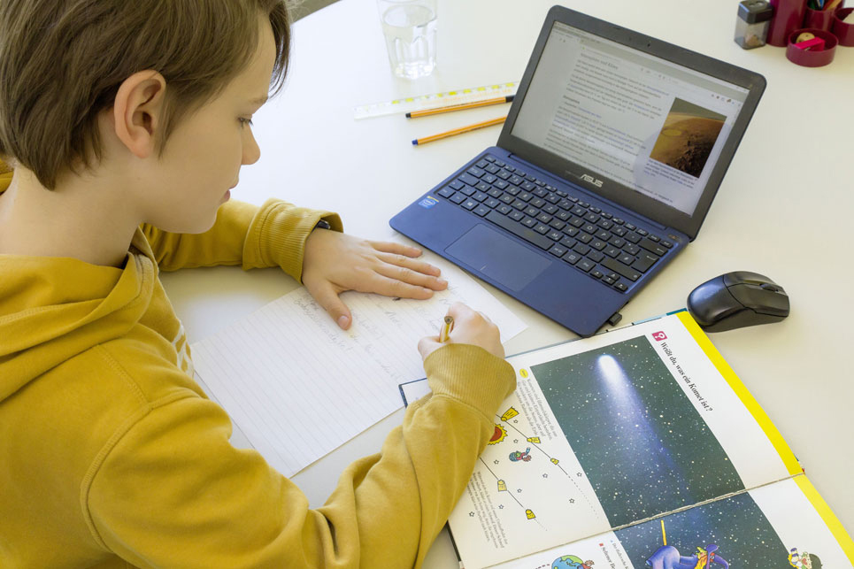 Junge mit Laptop am Schreibtisch beim Lernen
