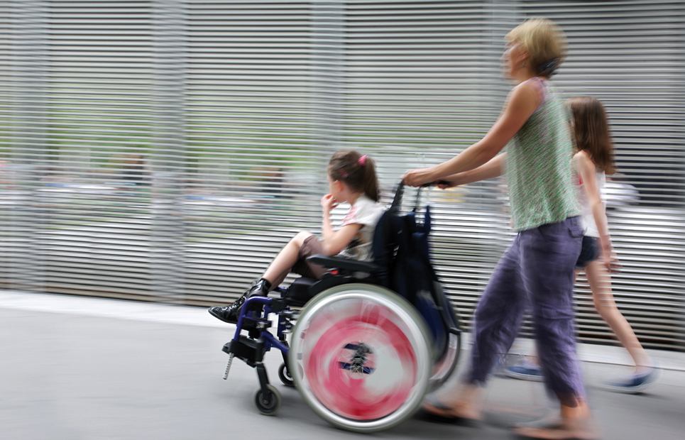 Eine Mutter schiebt ihr Kind im Rollstuhl.