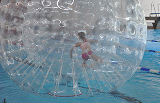 Kind in einem Wasserlaufball im Schwimmbecken des TaunaBades