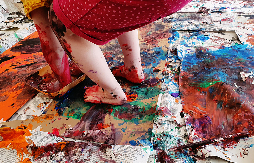 Ein Kind experimentiert mit Händen und Füßen mit Farbe
